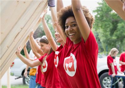Community volunteers in red shirts lifting a wooden frame